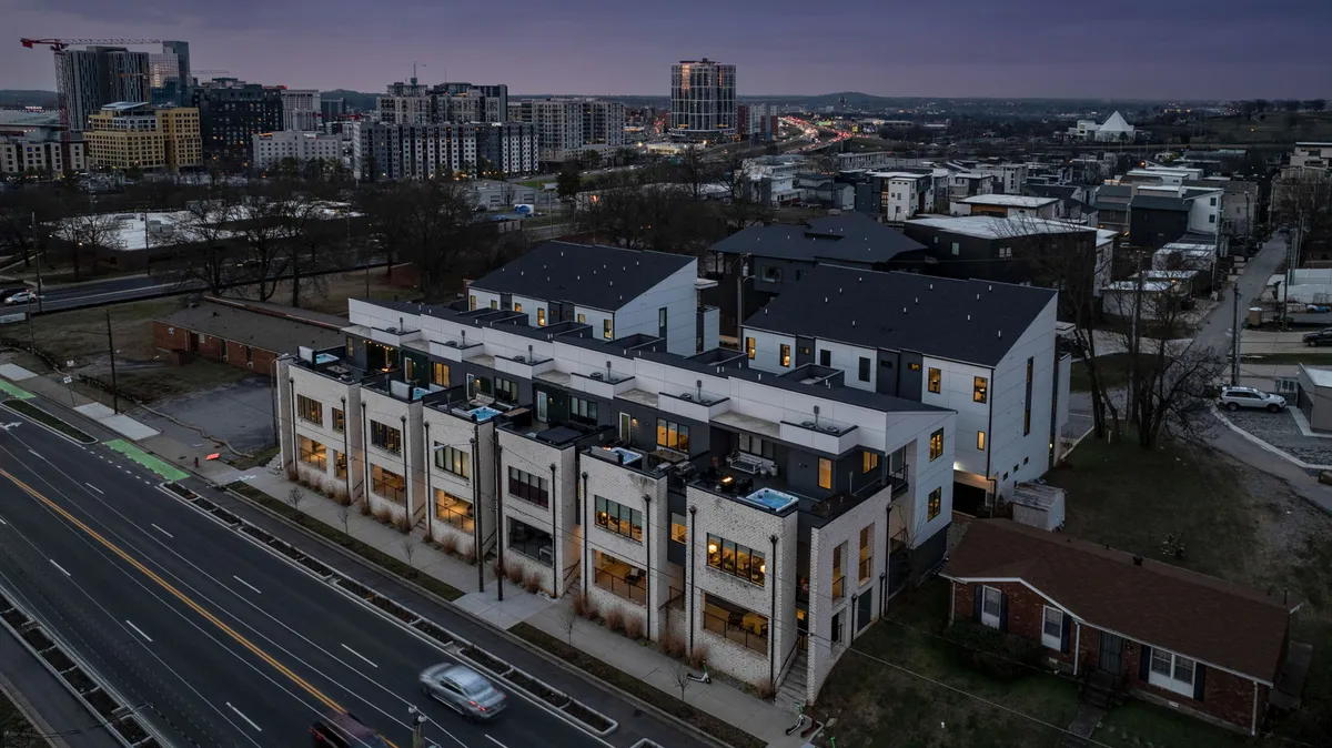 A striking exterior shot of modern townhouses set against the city skyline, with a vibrant street scene that hints at an urban lifestyle. The neighborhood feels contemporary and welcoming, ideal for business travelers seeking both privacy and proximity to downtown.