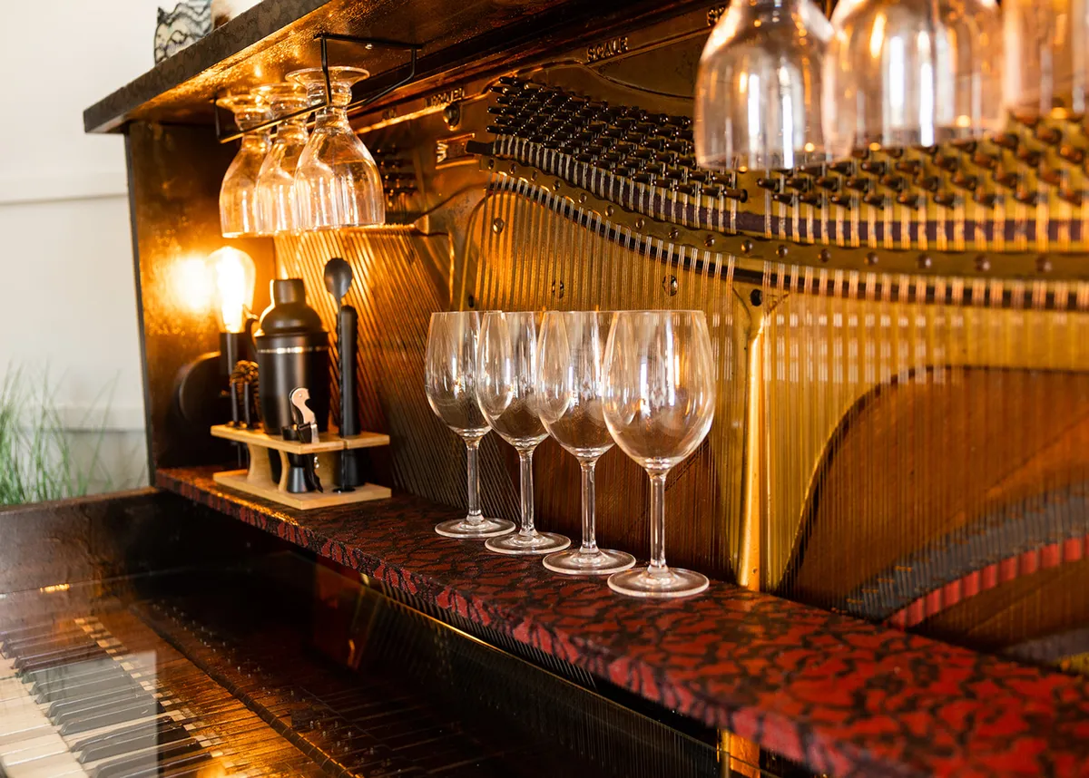 A stunning piano-bar setup featuring a sleek piano, elegant glassware, ambient lighting fixtures, and decorative items. The arrangement creates a focal point that blends music, socializing, and luxury.