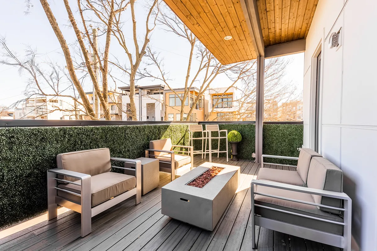 A cozy, inviting rooftop space with comfortable outdoor seating encircling a glowing fire pit, surrounded by greenery. The ambiance is serene, suggesting a perfect spot for sunset conversations, stargazing, or an intimate gathering with the city skyline as a subtle backdrop.